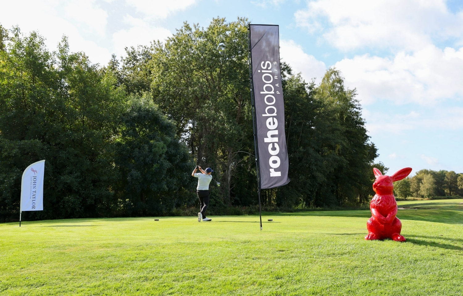 Golfeur qui effectue un swing entouré de beach flag roche bobois