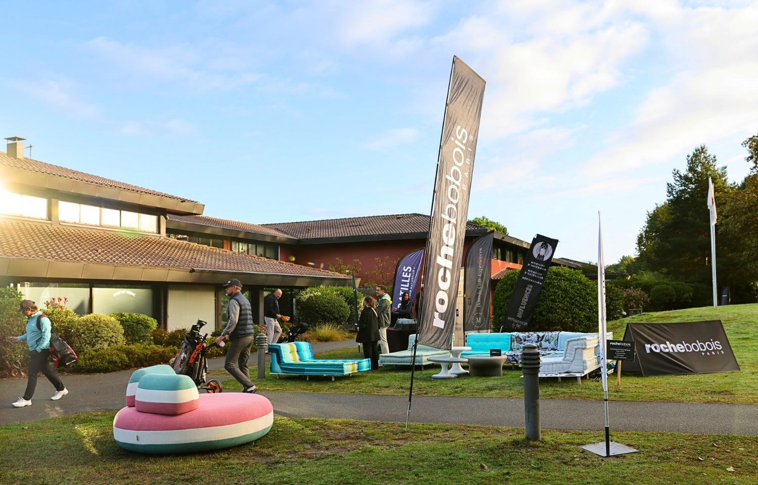 Installation de canapés et fauteuils à l'entrée d'un golf avec un beach flag de Roche Bobois